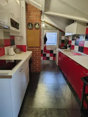 a kitchen with red and white cabinets and a brick wall at Katata Apartment in Podgorica
