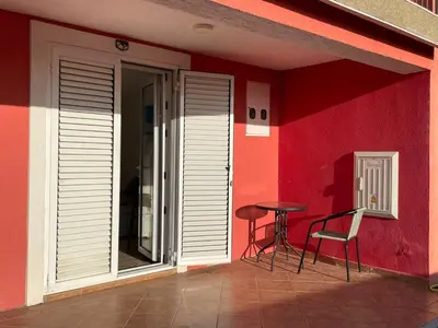 a red wall with a table and chairs on a patio at Teona-Apartments in Sutomore