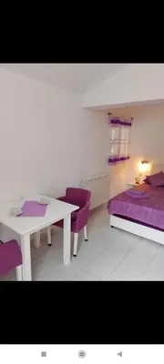 a room with a white table and purple chairs at Apartman Blazo in Škaljari