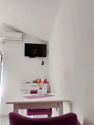 a kitchen with a table and two purple chairs at Apartman Blazo in Škaljari