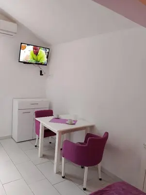 a dining room with a table and purple chairs at Apartman Blazo in Škaljari