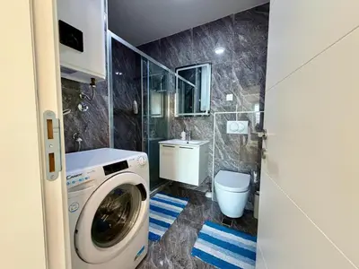 a bathroom with a washing machine and a toilet at Comfortable City Apartment in Bar