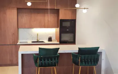 a kitchen with a counter with two green chairs at City Living with Style - Elegant One-Bedroom Apartment in Podgorica