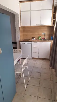 a kitchen with white cabinets and a table and chairs at Simpi in Pržno
