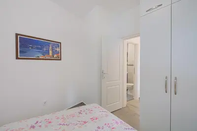 a white bedroom with a bed and a picture on the wall at Apartment Kotor Bay in Kotor