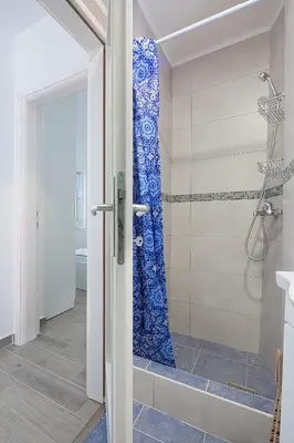 a bathroom with a shower with a blue shower curtain at Apartment Kotor Bay in Kotor