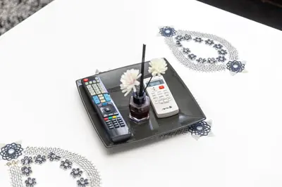 two remote controls and a vase with flowers on a table at PrivatHomeUlcinj2 in Ulcinj