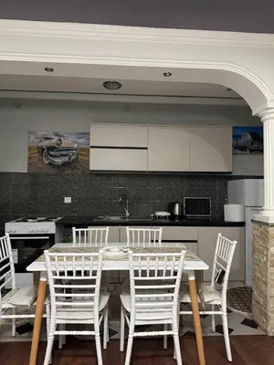 a kitchen with a table and white chairs in a kitchen at PrivatHomeUlcinj2 in Ulcinj