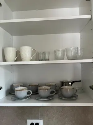 a shelf with several cups and bowls on it at Apartman Lux M Residence PG in Podgorica