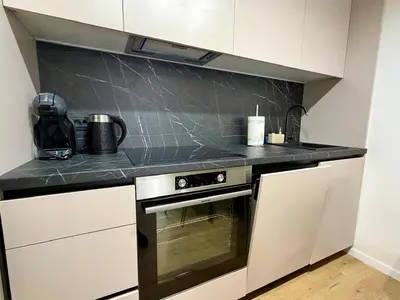 a kitchen with white cabinets and a black counter top at Apartment by the sea in Dobra Voda