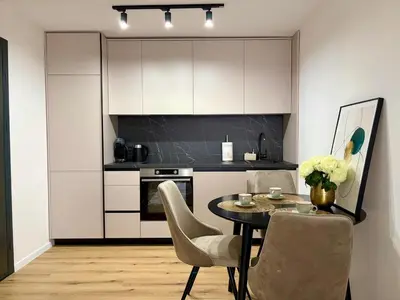 a kitchen with a table and chairs and a kitchen with white cabinets at Apartment by the sea in Dobra Voda