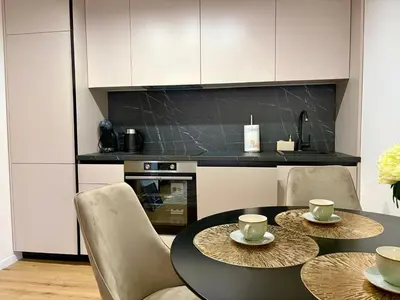 a kitchen with a black table and chairs and a kitchen with white cabinets at Apartment by the sea in Dobra Voda