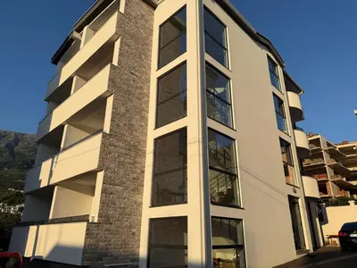 a tall white building with large windows at Apartment by the sea in Dobra Voda