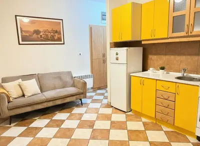 a kitchen with a couch and a kitchen with yellow cabinets at Charming terrace studio in Podgorica