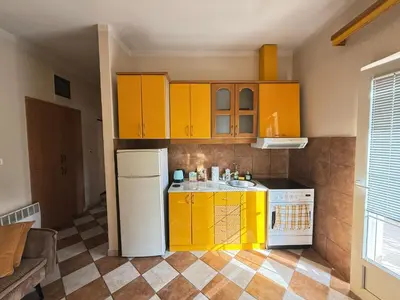 a kitchen with yellow cabinets and a white refrigerator at Charming terrace studio in Podgorica
