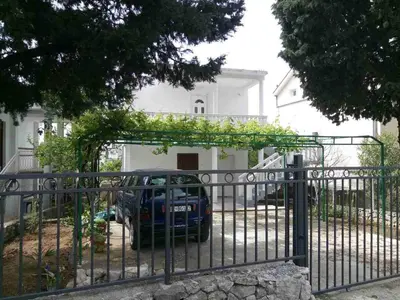 a car parked behind a gate in front of a house at Apartments Dubrava 106 in Dobra Voda
