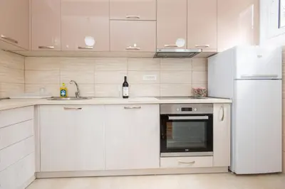 a kitchen with white cabinets and a refrigerator at GALIOT Apartment in Škaljari