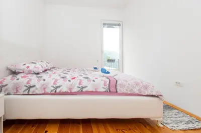 a white bed with a pink comforter and a window at GALIOT Apartment in Škaljari