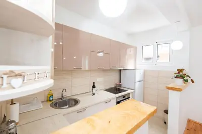 a white kitchen with a sink and a refrigerator at GALIOT Apartment in Škaljari