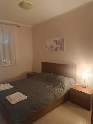 a bedroom with a bed and a table with a lamp at Apartman D3 in Podgorica