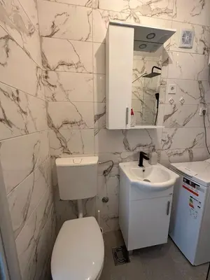 a white bathroom with a toilet and a sink at Andrea Apartment in Podgorica