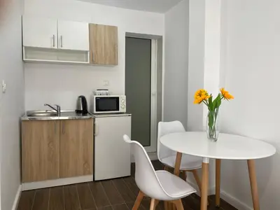 a small kitchen with a table and a white table and chairs at Veselinka Apartments & Rooms in Budva