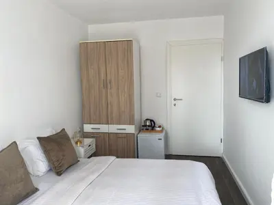 a bedroom with a white bed and a wooden cabinet at Veselinka Apartments & Rooms in Budva