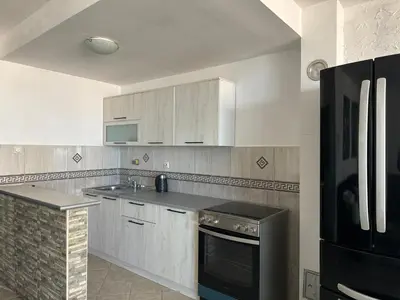 a kitchen with white cabinets and a black refrigerator at Veselinka Apartments & Rooms in Budva