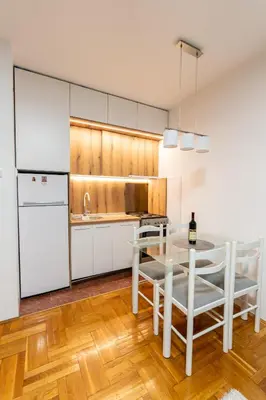 a kitchen with white cabinets and a table with chairs at Rajka Lux in Podgorica