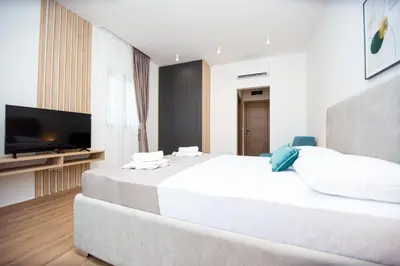 a bedroom with a large bed and a flat screen tv at Apartments Sirena - Modern stay with free parking in Budva