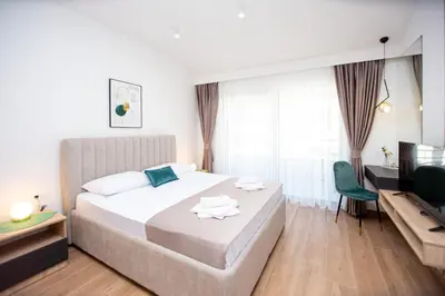 a bedroom with a large bed and a television at Apartments Sirena - Modern stay with free parking in Budva