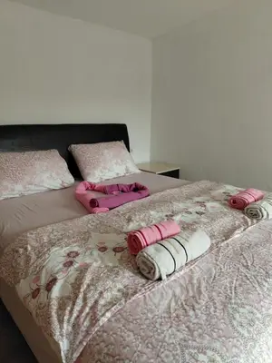 a bed with pink and white blankets and pillows on it at Studio apartman Milena 1 in Podgorica