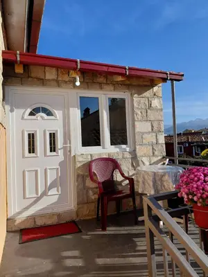 a small house with a white door and a chair at Studio apartman Milena 1 in Podgorica