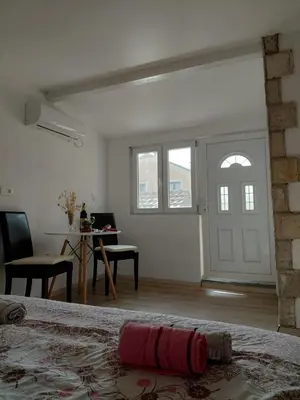 a white room with a bed and a table and a desk at Studio apartman Milena 1 in Podgorica