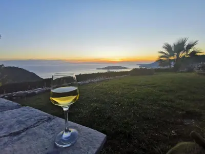 a glass of wine sitting on a ledge with the sunset at Lux Villa Provence in Budva