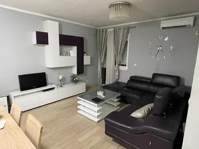 a living room with a black leather couch and a clock at Apartment Peace in Podgorica