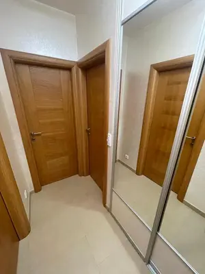 a hallway with two wooden doors and a mirror at Apartment Peace in Podgorica