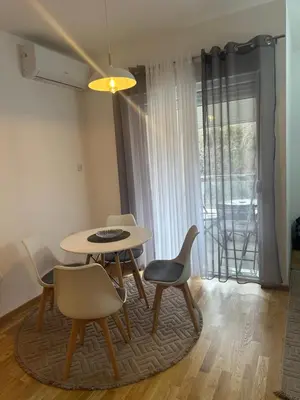 a dining room with a table and chairs and a window at Studio apartman in Budva
