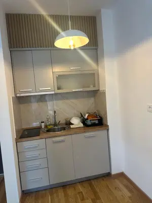 a kitchen with white cabinets and a sink at Studio apartman in Budva