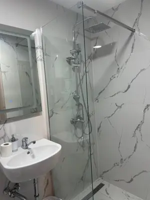 a white bathroom with a sink and a shower at Studio apartman in Budva