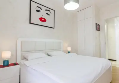 a white bedroom with a white bed with a red lipstick at DeLux and Urban apartments Hotel Tre Canne Budva in Budva