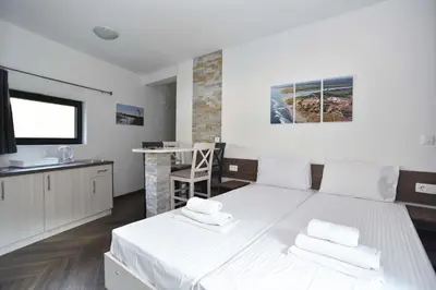 a bedroom with a large white bed and a kitchen at Lux Čanj in Čanj