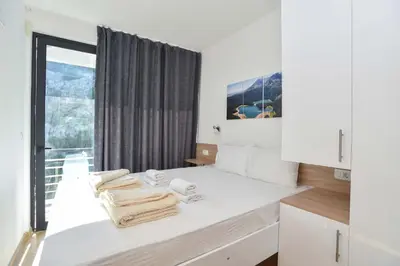 a white kitchen with a window and towels on a counter at Lux Čanj in Čanj