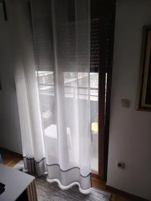 a window with white curtains in a room at Sicilija apartment in Podgorica