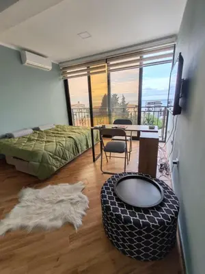 a bedroom with a bed and a table and a room with a balcony at Cherry in Dobra Voda