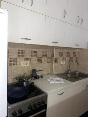 a kitchen with white cabinets and a stove and a sink at Apartment little paradise in Podgorica