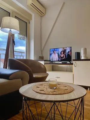 a living room with a table and a tv at Apartment little paradise in Podgorica