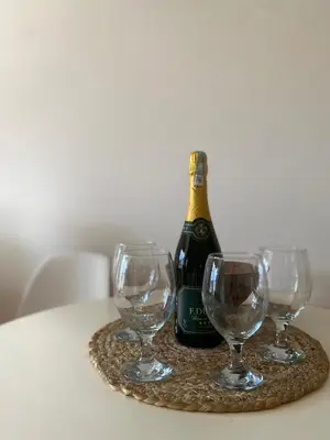 a bottle of champagne and three wine glasses on a table at Apartment little paradise in Podgorica