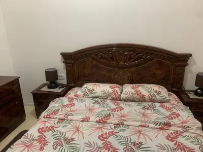 a bed with a wooden headboard and two night stands at Apartman SA&BO in Podgorica