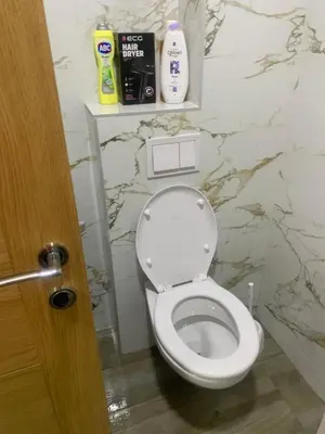 a white toilet in a bathroom with a marble wall at Apartman SA&BO in Podgorica